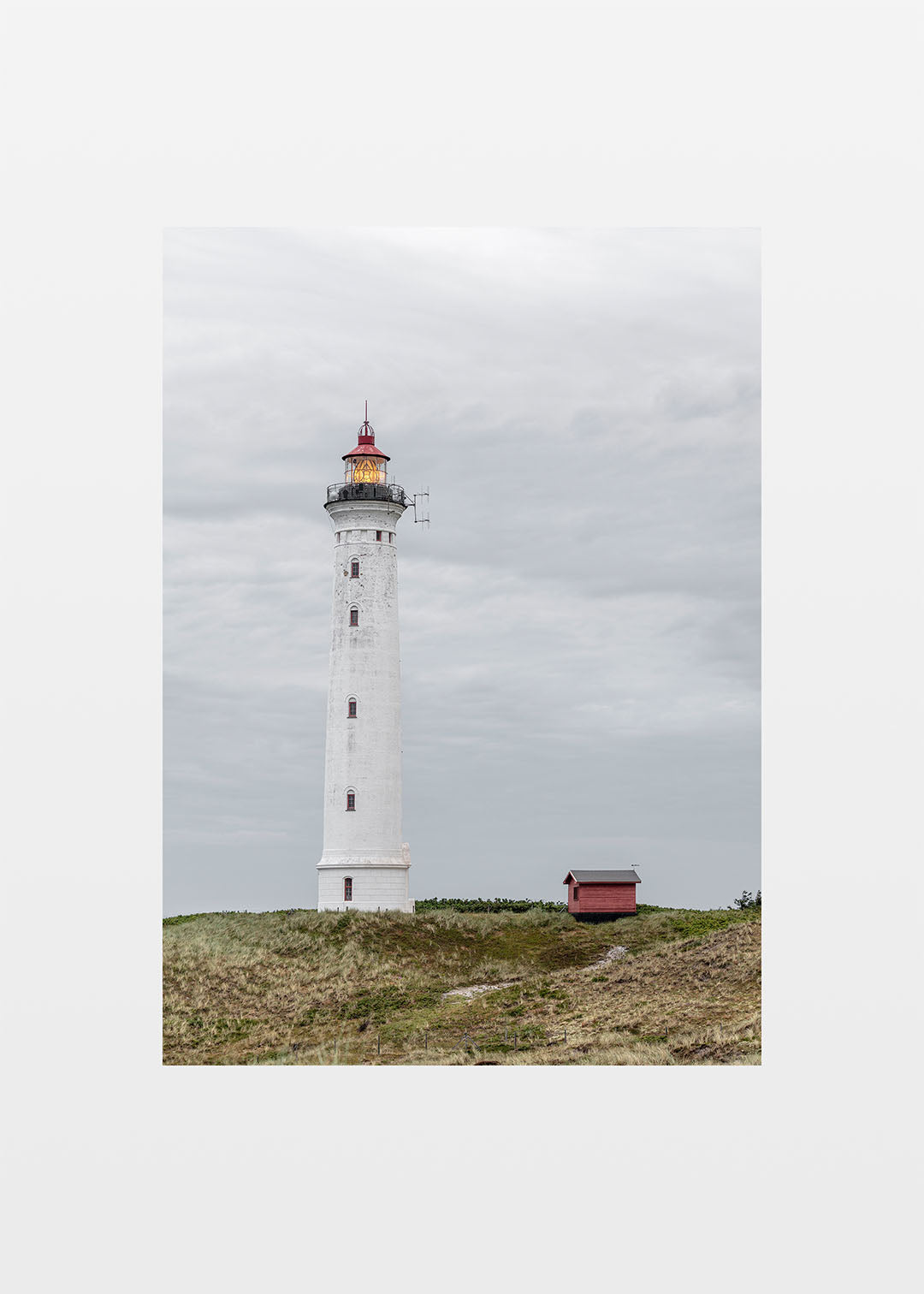 Lyngvig Fyr ved Hvide Sande med klitter, grå himmel og tændt lanterne